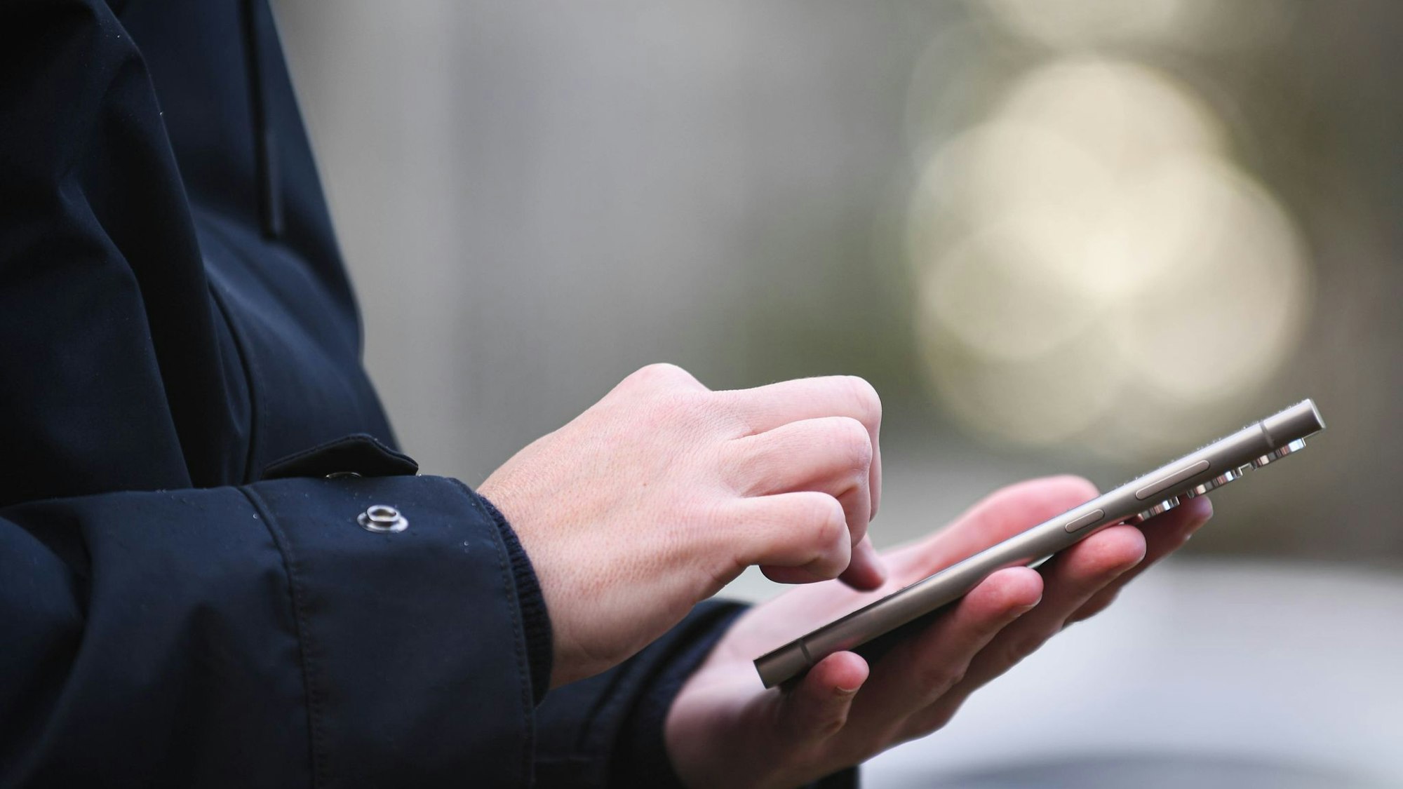 Hände, die ein Handy halten, in Nahaufnahme. Die Person drückt gerade auf eine Anwendung.