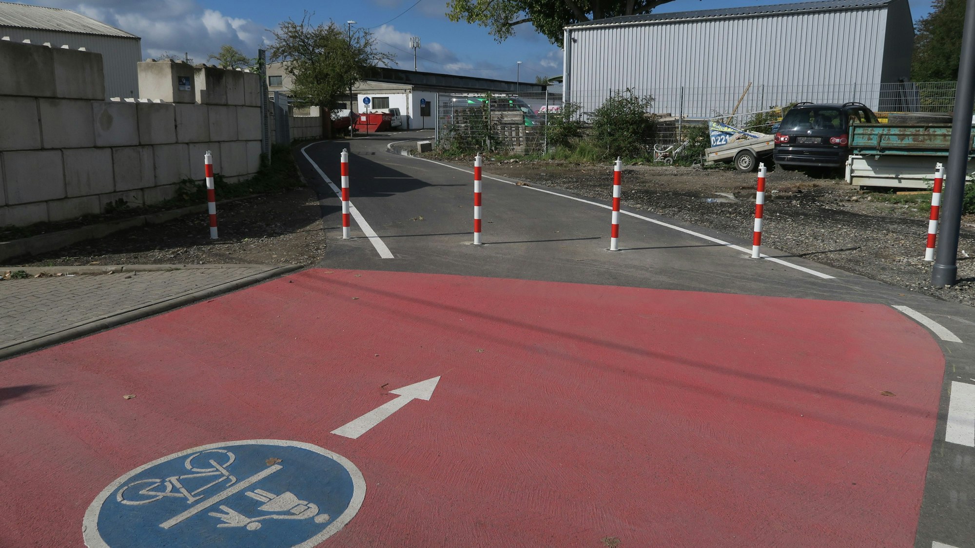 Ein Rad- und Fußwegmarkierung ist frisch aufgebracht auf einer schmalen asphaltierten Straße.