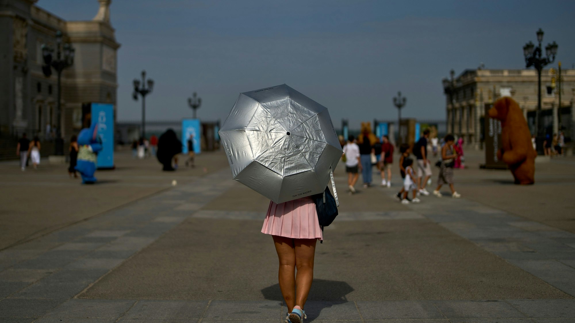 Eine Frau schützt sich mit einem Schirm vor Sonne und Hitze.
