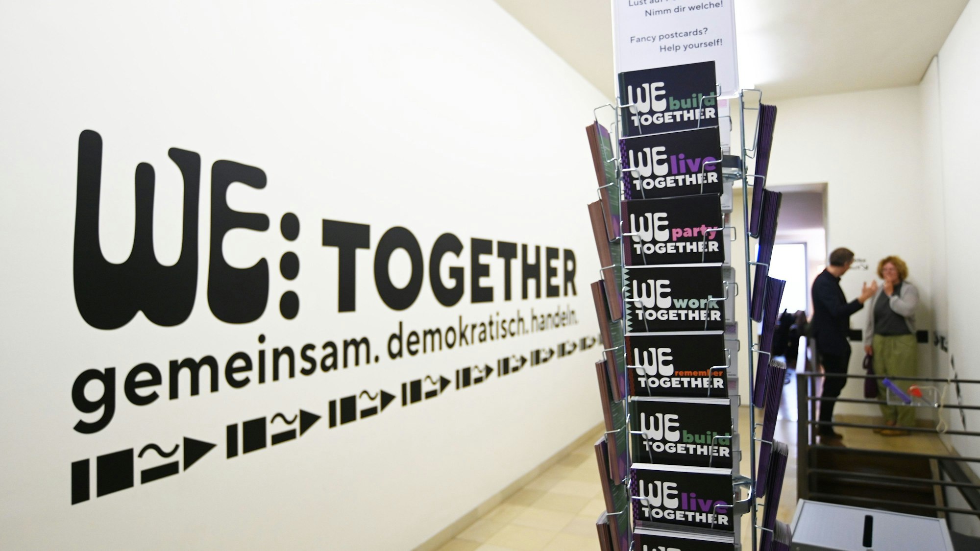 Schriftzug an der Wand und Infokärtchen der neuen Ausstellung „We … together“