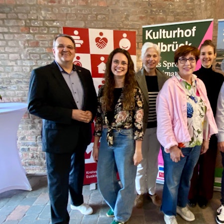 Zwei Männer und vier Frauen stehen nebeneinander und lächeln in die Kamera.