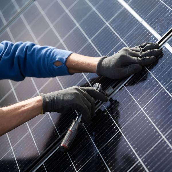 Ein Mann montiert Photovoltaikmodule auf dem Dach eines Wohnhauses. (Archiv)