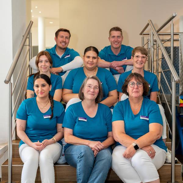 Acht Mitglieder des medizinischen Teams der neuen Praxis sitzen auf einer Treppe.
