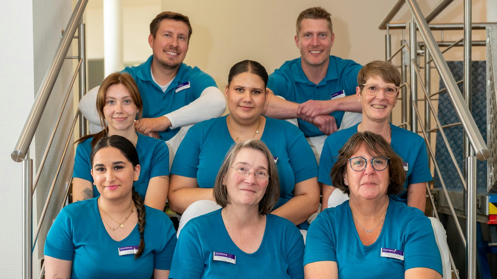 Acht Mitglieder des medizinischen Teams der neuen Praxis sitzen auf einer Treppe.