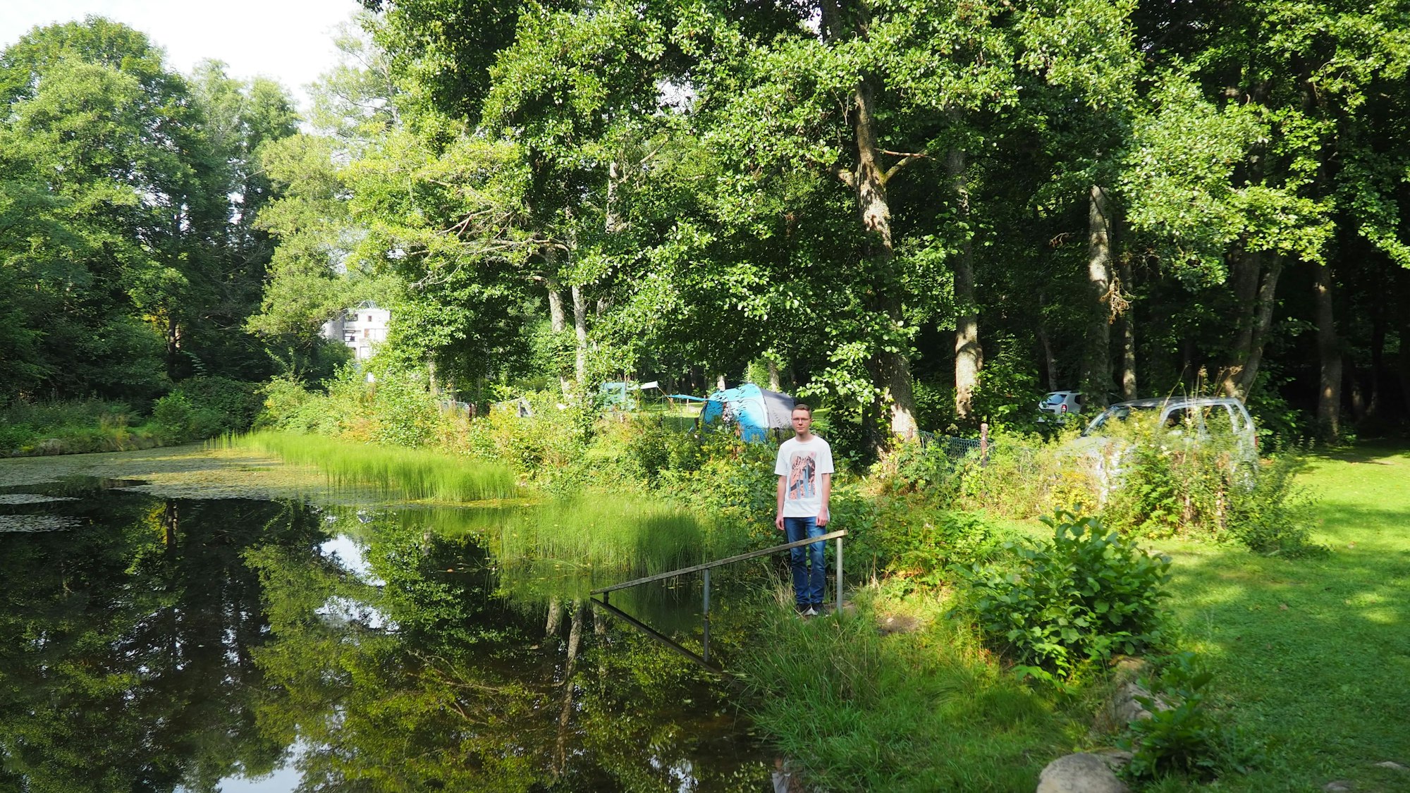 Alexander Wagner steht am Ufer eines Teichs inmitten der grünen Landschaft.