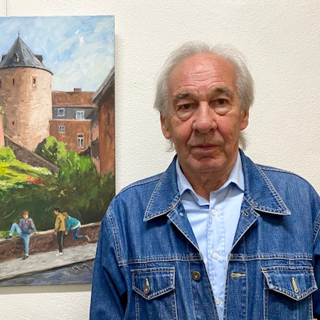 Der Künstler steht rechts neben einem seiner Ölgemälde mit einer Stadtansicht von Euskirchen.