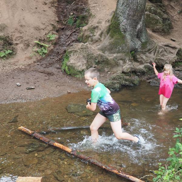 Zwei Kinder spielen im seichten Wasser eines Baches.