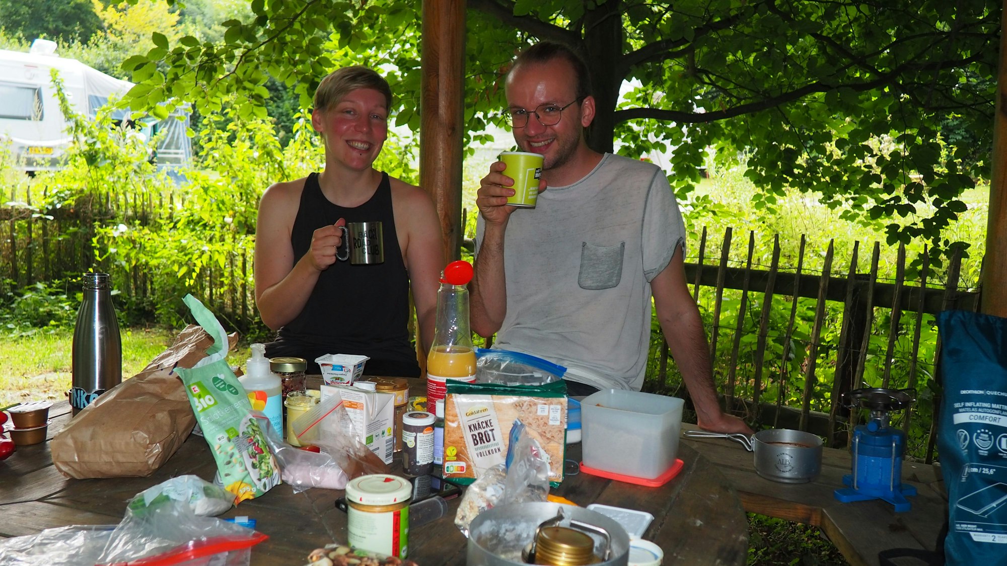 Amelie Frerichs (l.) und Kilian Kuhlendahl sitzen unter Bäumen am gedeckten Frühstückstisch.