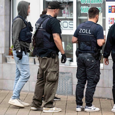 Das Bild zeigt den Moment der Durchsuchung, bei dem die Beamten in den Kiosk gehen.