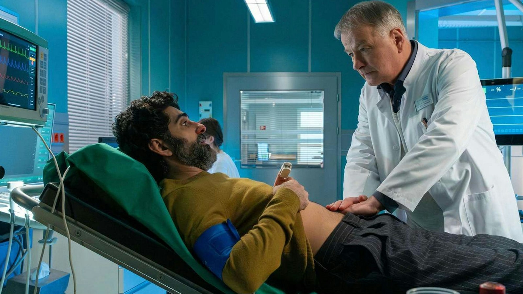 Dieser Fehler entrüstete die Fans von „In aller Freundschaft“: Dr. Heilmann (Thomas Rühmann) untersucht Razak Amari (Reza Brojerdi), trägt dabei aber nicht die Brille, die ihm gerade verordnet wurde. (Bild: MDR/Sebastian Kiss)