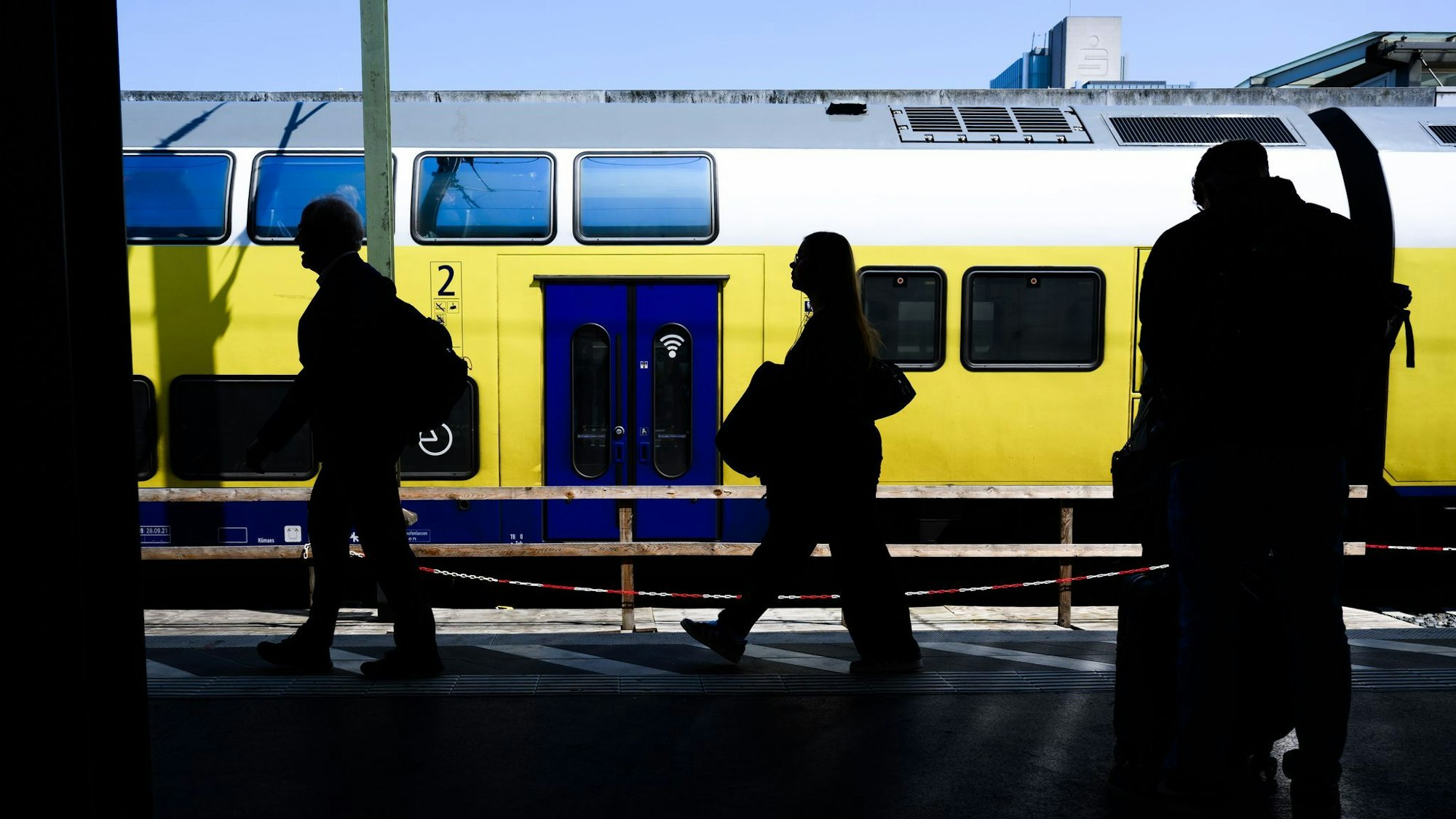 Personen gehen am Bahnsteig entlang.