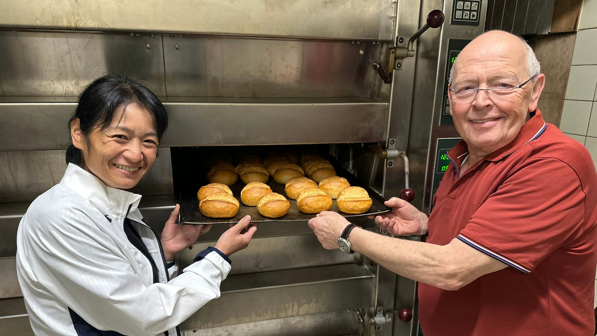 Bäckermeister Stephan Profittlich am großen Ofen, den er 2015 für 80.000 Euro neu eingebaut und jetzt für 5000 Euro verkauft hat. Neben ihm Saeko Haratake, die bei ihm in die Lehre ging.