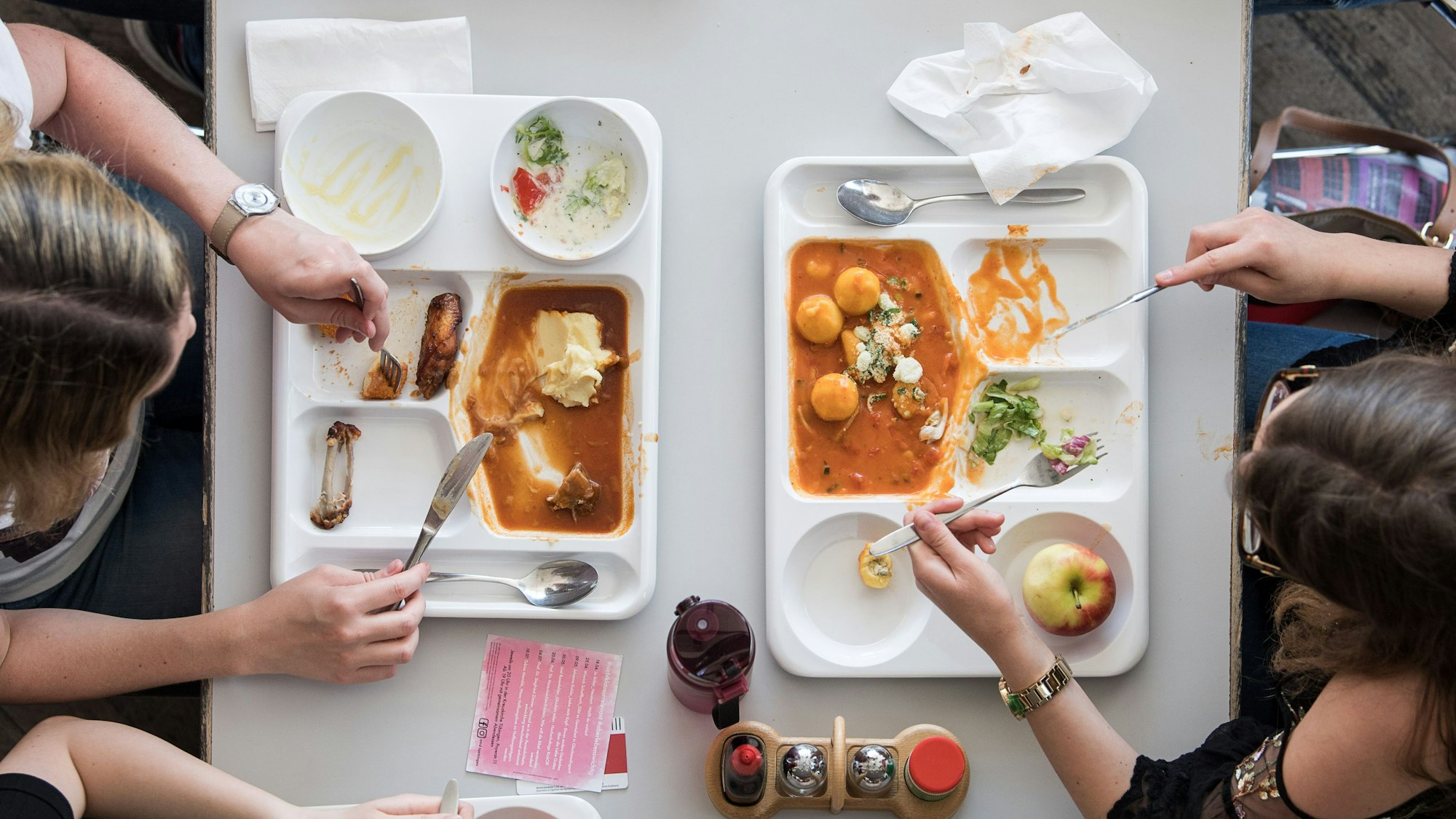 Zwei Studentinnen essen in einer Mensa.