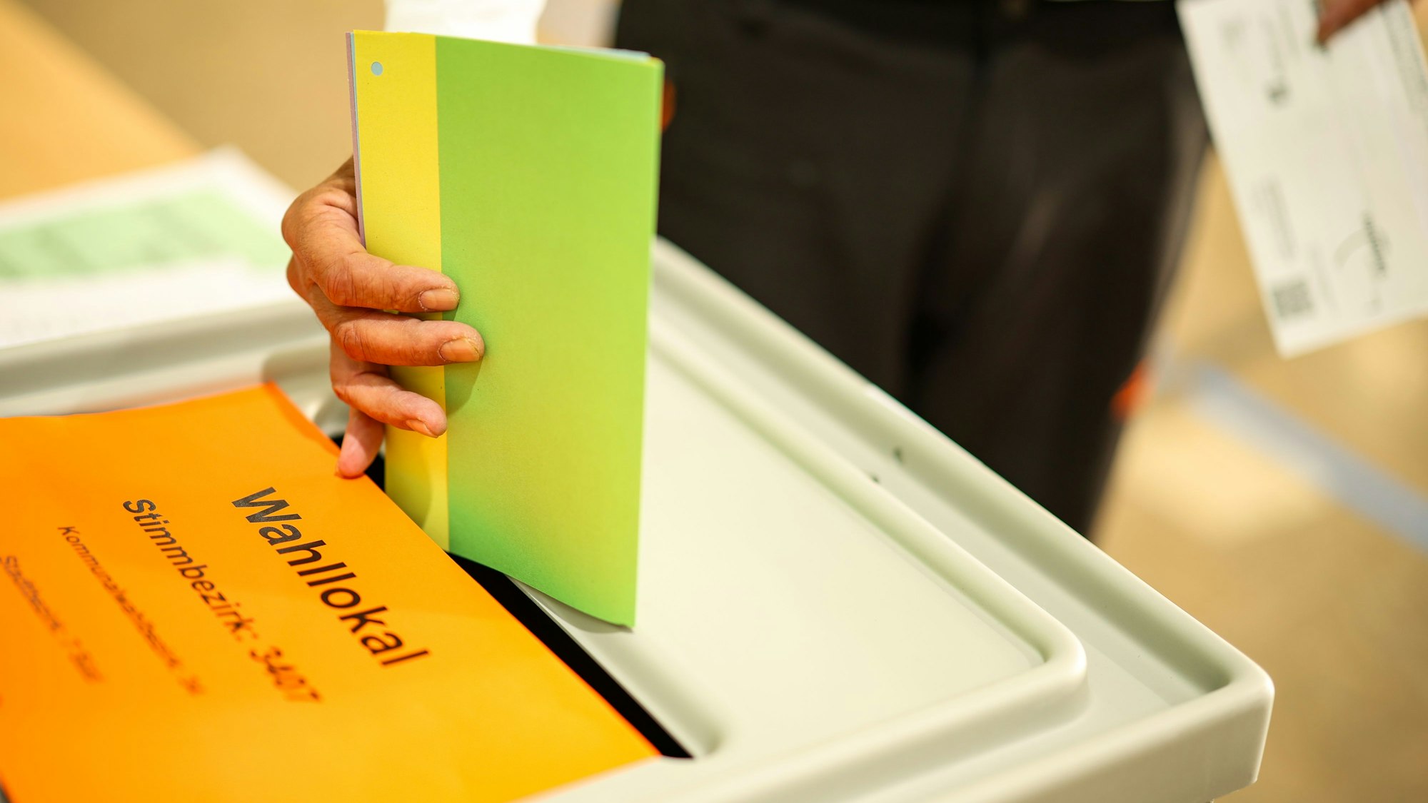 Ein Mann wirft seine Stimmzettel in eine Wahlurne. Am 28. September gibt es Stichwahlen, unter anderem in Reichshof und Morsbach.