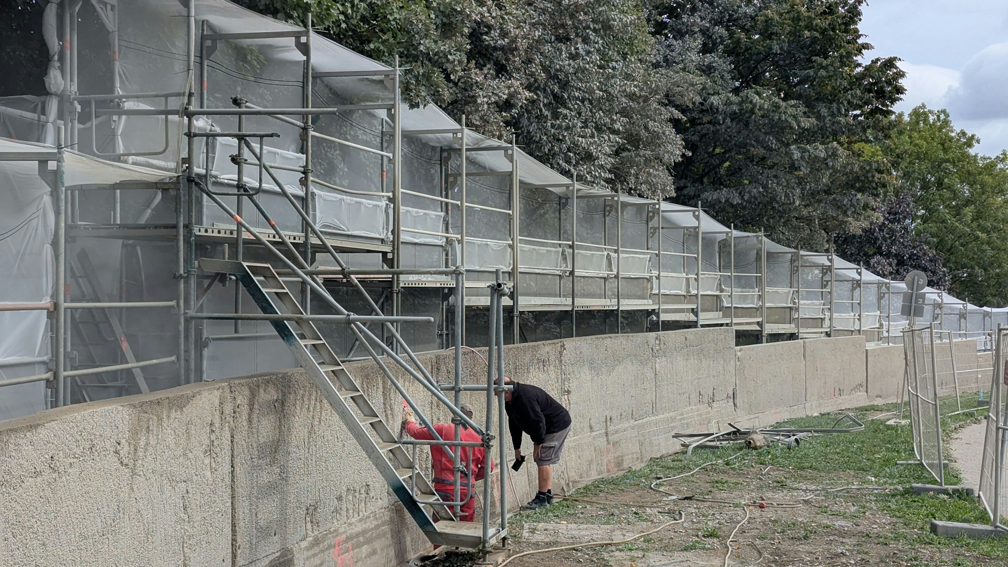 Das Foto zeigt die eingerüstete und teilweise mit Plastikplanen verhüllte Mauer.