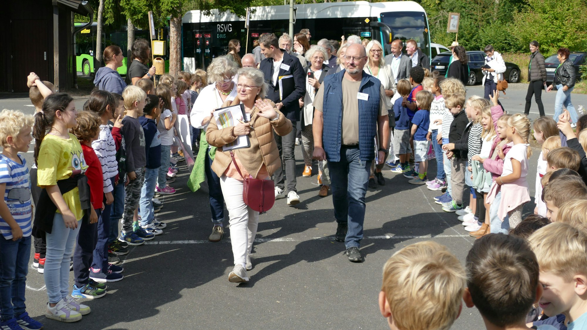 Menschen gehen durch ein Spalier, das Grundschüler für sie bilden.