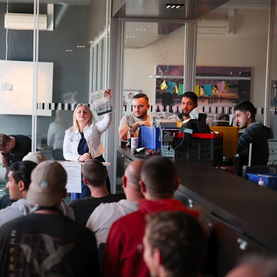 Die Auktionatorin zeigt ein zur Versteigerung stehendes Handy.