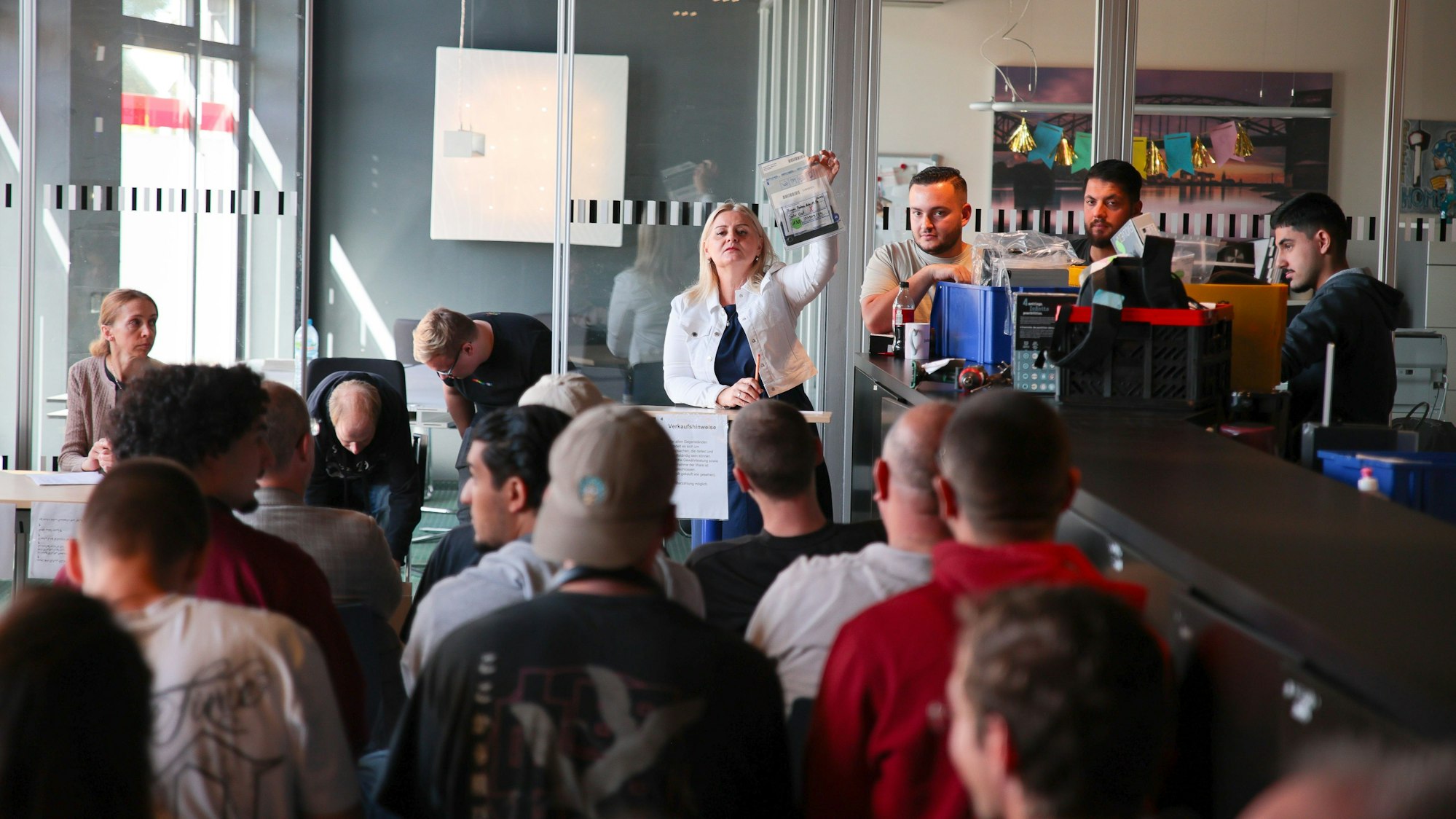 Die Auktionatorin zeigt ein zur Versteigerung stehendes Handy.