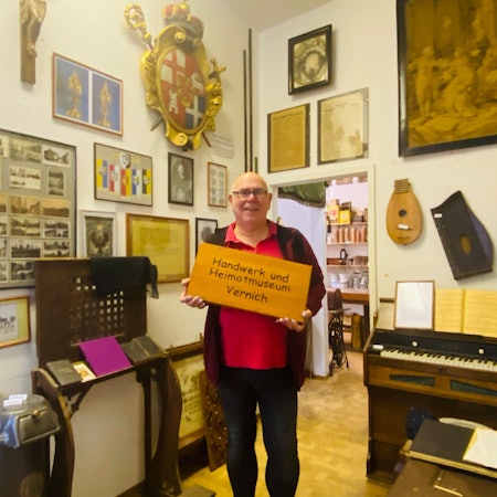 Karl-Heinz Nauroth steht in einem Museumsraum voller Exponate, darunter Instrumente und Bilder.