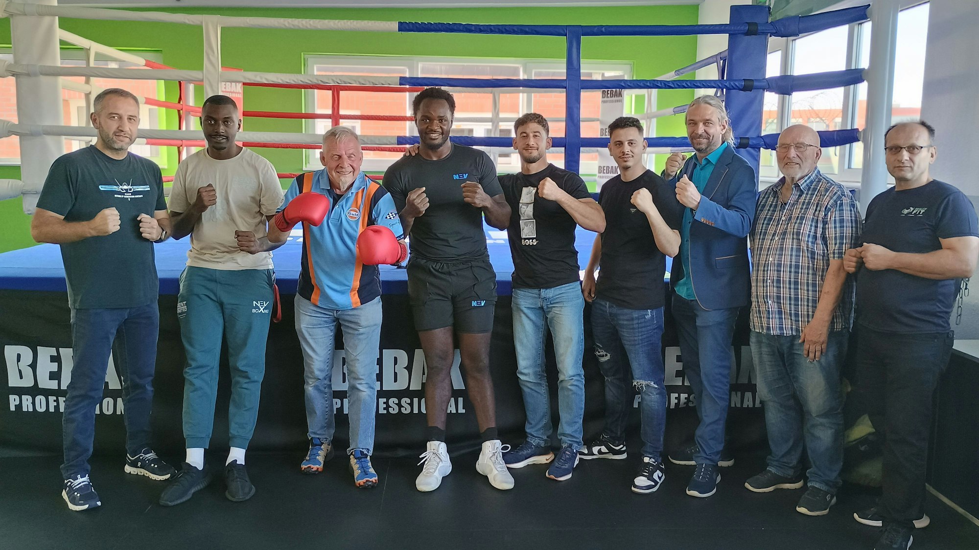 Die Beteiligten stehen in einer Reihe zu recken die Fäuste, hinter ihnen der Ring.