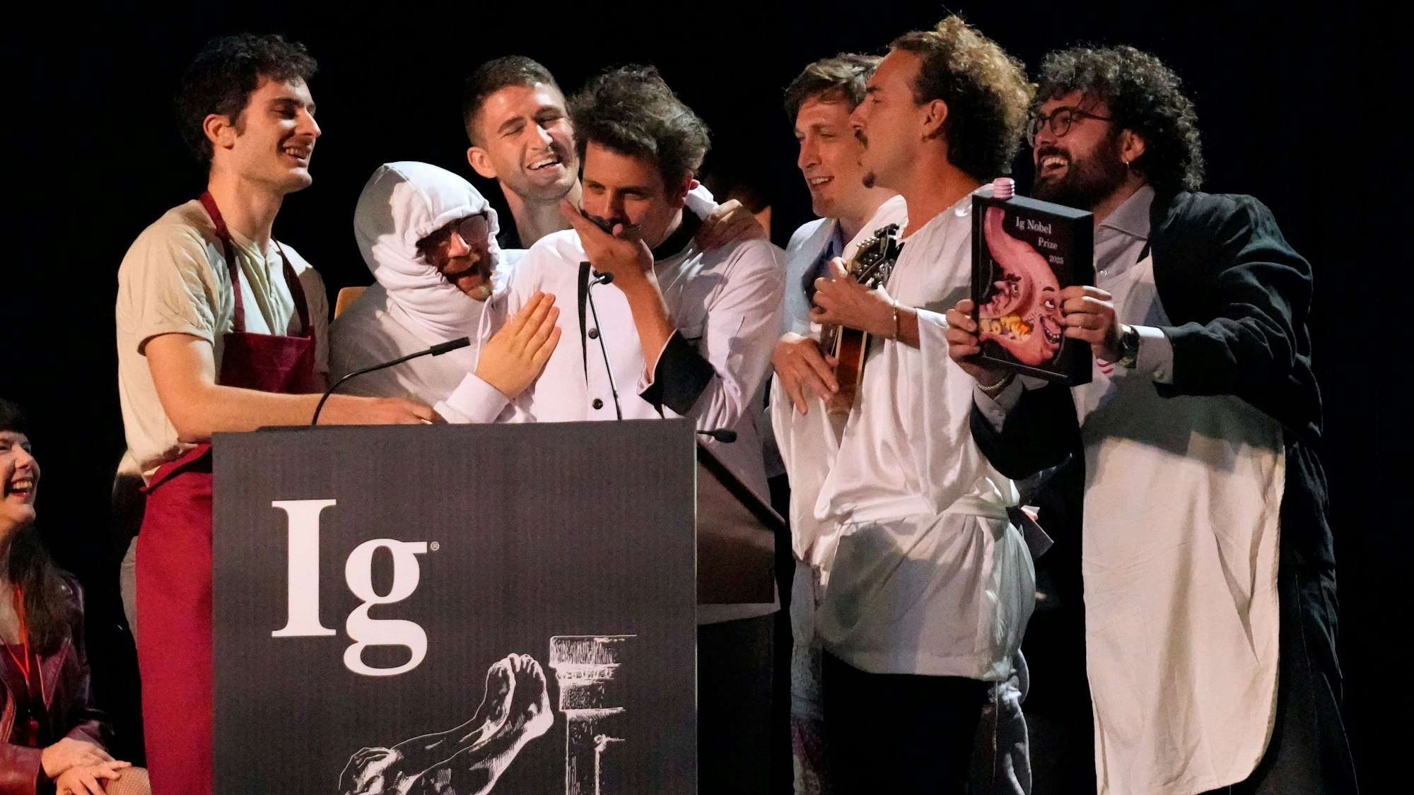 Der Ig-Nobelpreis für Ernährung wird von Daniele Dendi, Gabriel H. Segniagbeto, Roger Meek und Luca Luiselli entgegengenommen, die untersucht haben, inwieweit eine bestimmte Eidechsenart bestimmte Sorten von Pizza isst.