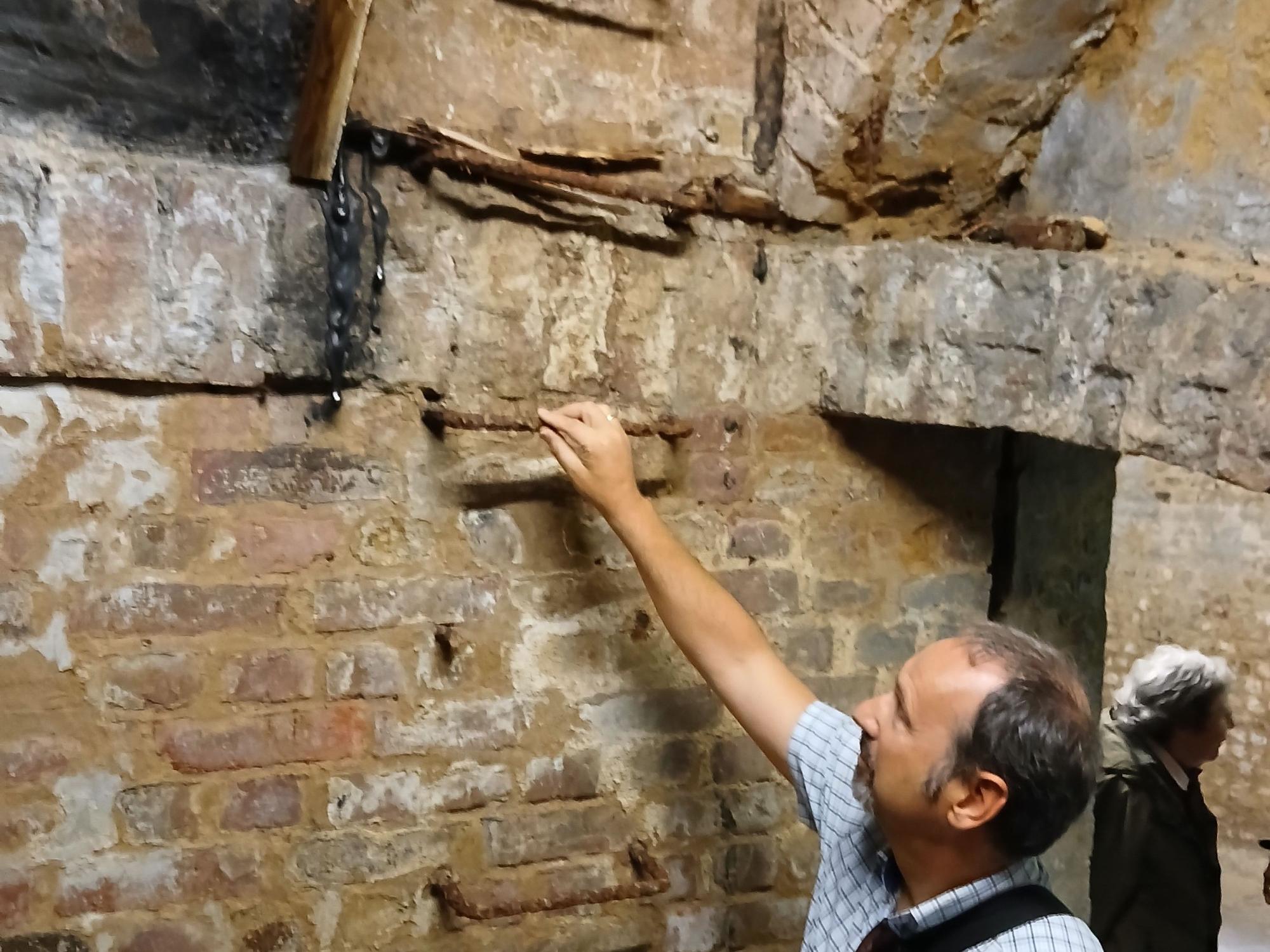 Hans-Gerd Dick steht an einer gemauerten Wand in einem Kellergewölbe an einer eisernen Steigleiter, die einst in ein Dienstgebäude führte.