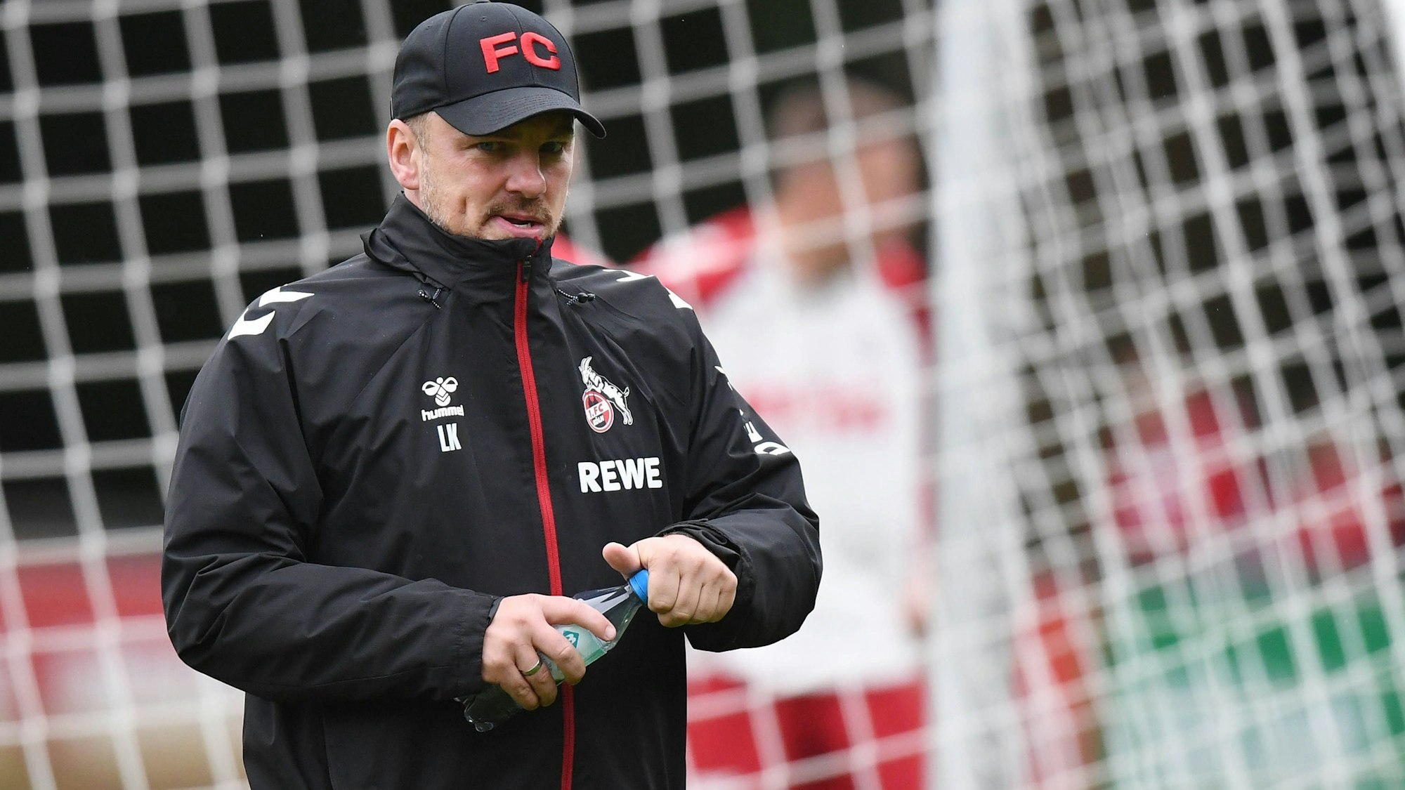 Lukas Kwasniok schraubt eine Wasserflasche in seiner Hand zu.