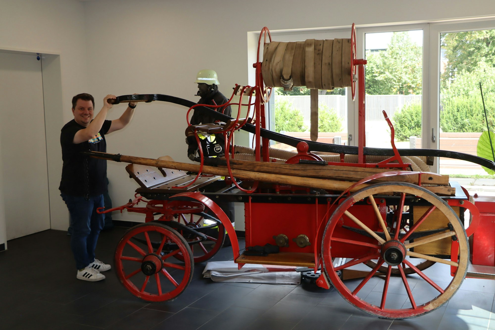 Auf dem Bild ist ein alter roter Spritzenwagen mit einem Mann zu sehen.