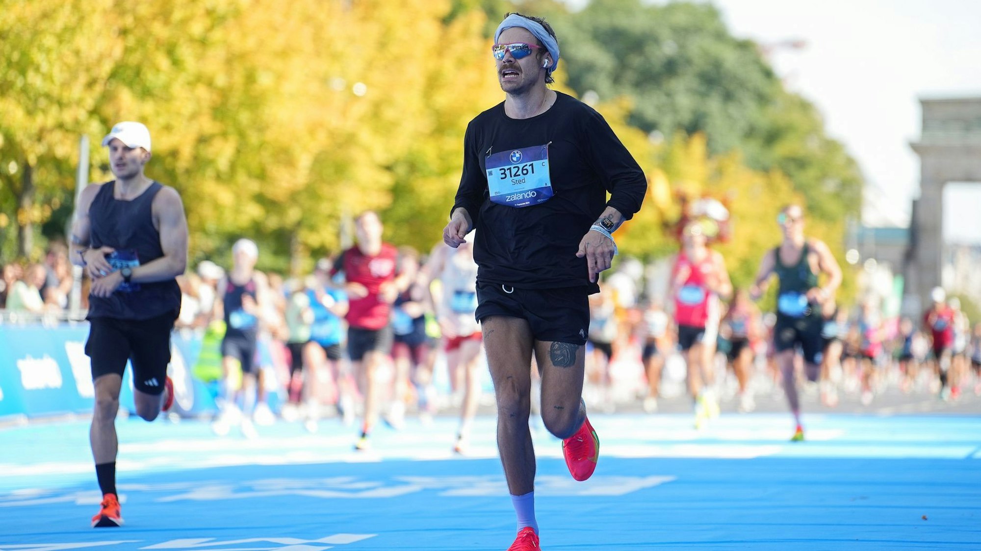 Der britische Sänger und Schauspieler Harry Styles (r) startete unter falschem Namen beim Berlin-Marathon.