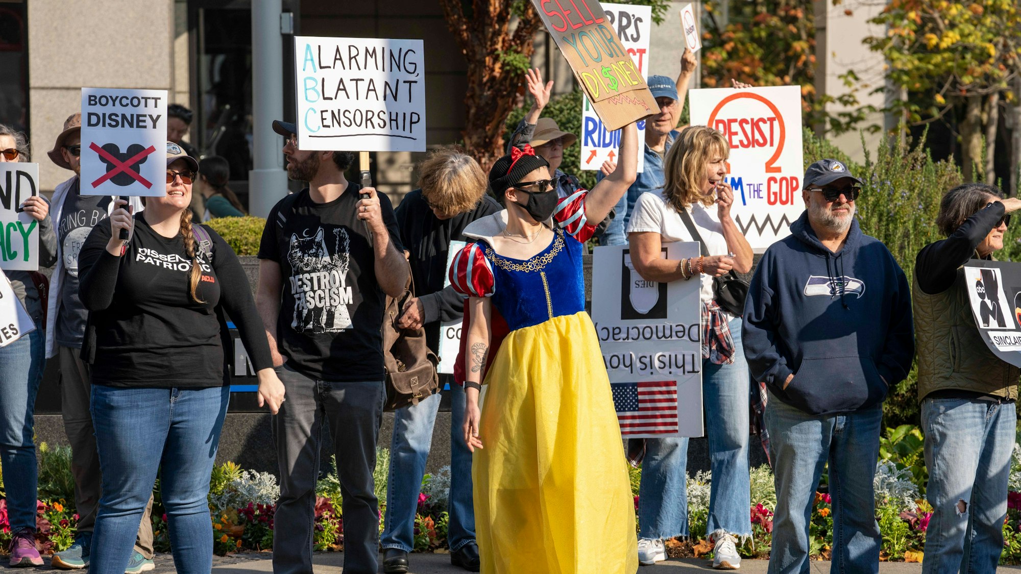 dpatopbilder - 20.09.2025, USA, Seattle: Menschen versammeln sich vor dem Hauptquartier von KOMO-TV, dem zur Sinclair Broadcast Group gehörenden ABC-Fernsehsender in Seattle, um gegen die Absetzung der Late-Night-Show Jimmy Kimmel Live! durch ABC zu protestieren. Die Demonstranten hielten Schilder zur Unterstützung von Jimmy Kimmel und der durch den ersten Verfassungszusatz geschützten Redefreiheit. Auf einigen Schildern wurde auch zum Boykott von Disney und ABC aufgerufen. Hier sind einige der Demonstranten als Disney-Prinzessinnen verkleidet.