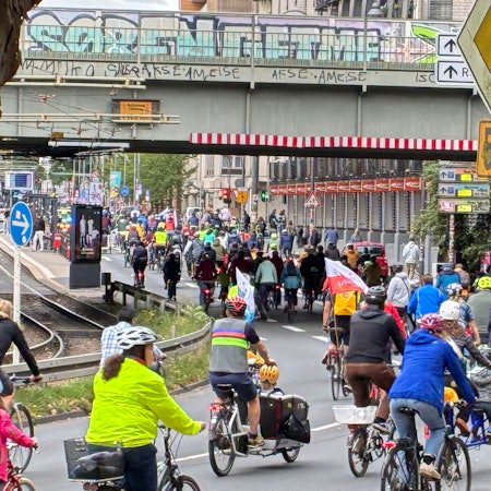 Hunderte Radfahrerinnen und Radfahrer fahren gedrängt auf einer Straße.