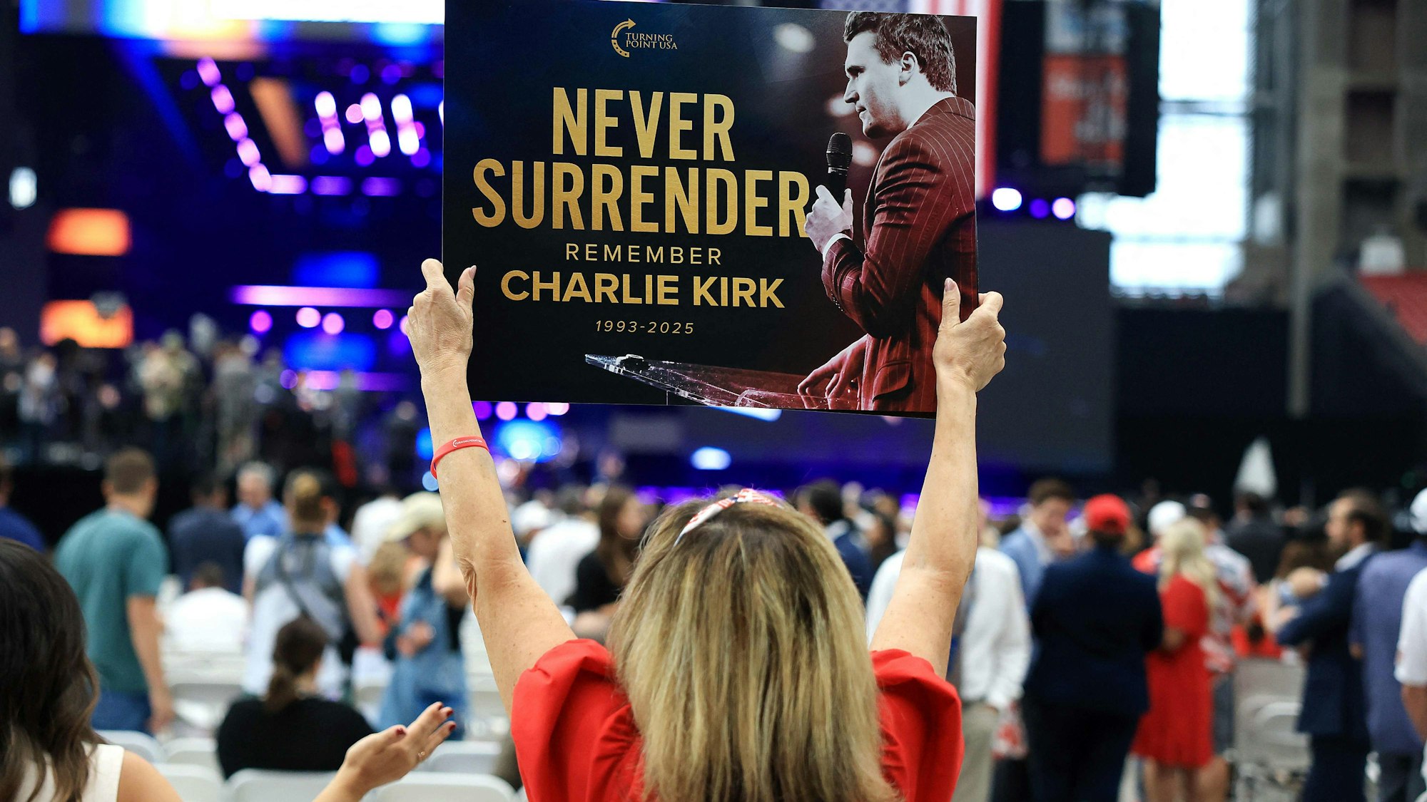 Ein Teilnehmer hält vor der Gedenkfeier für den politischen Aktivisten Charlie Kirk am 21. September 2025 im State Farm Stadium ein Schild mit der Aufschrift „Never Surrender“ (Niemals aufgeben) hoch.