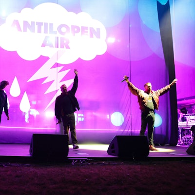 Drei Musiker winken von der Bühne ins Publikum.