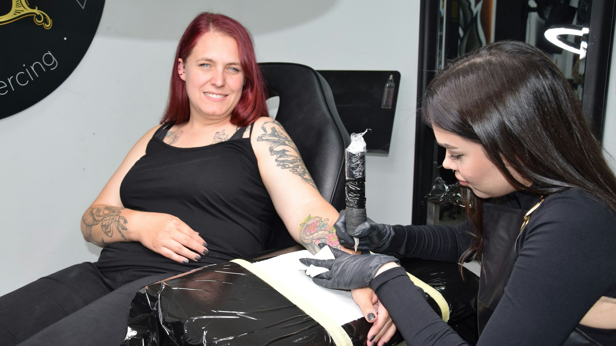 Das Foto zeigt eine Frau, die tätowiert wird.
