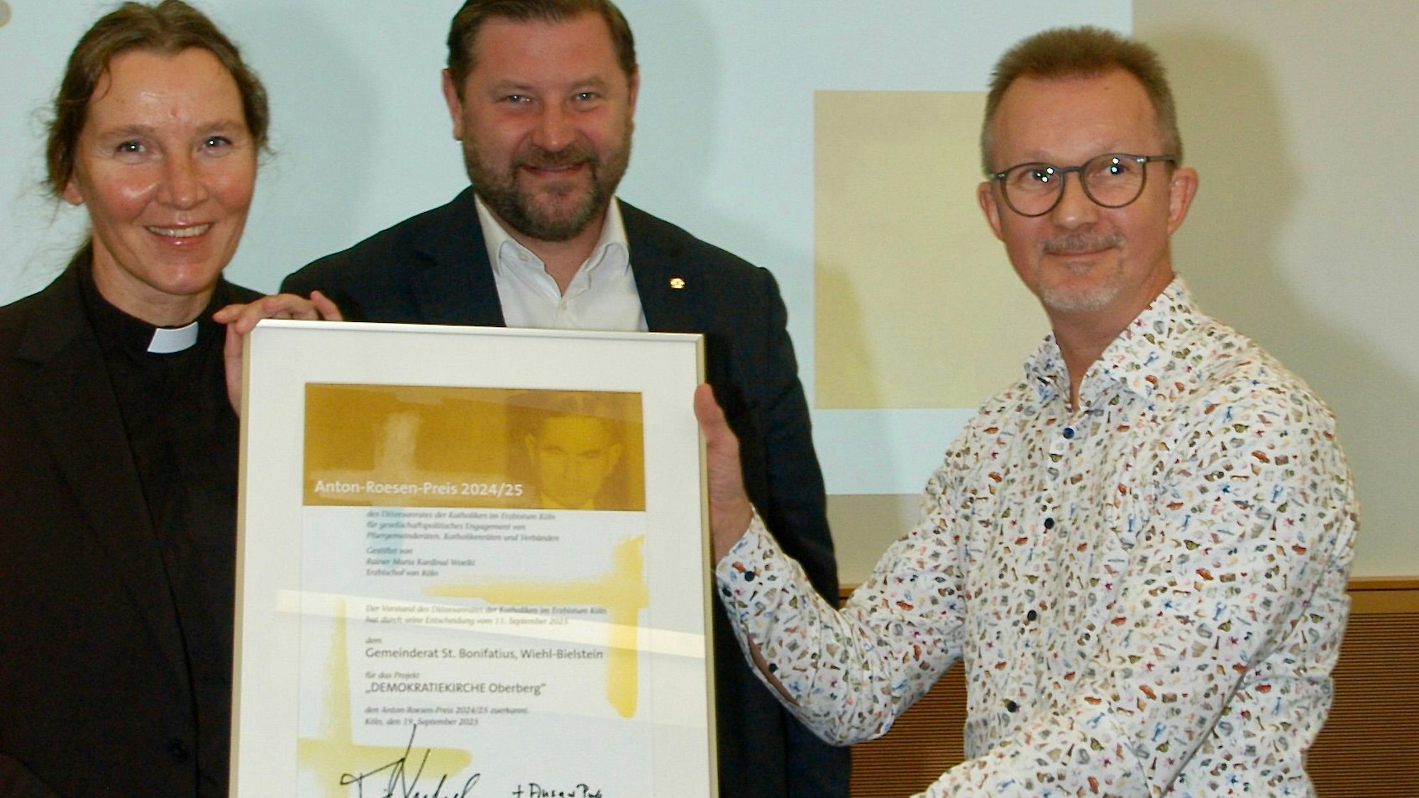 Das Foto zeigt drei Personen mit einer urkunde