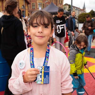 Ida, 8 Jahre, präsentiert beim Weltkindertag ihre Abzeichen, die sie bei der Rallye am Rheinauhafen bekommen hat.