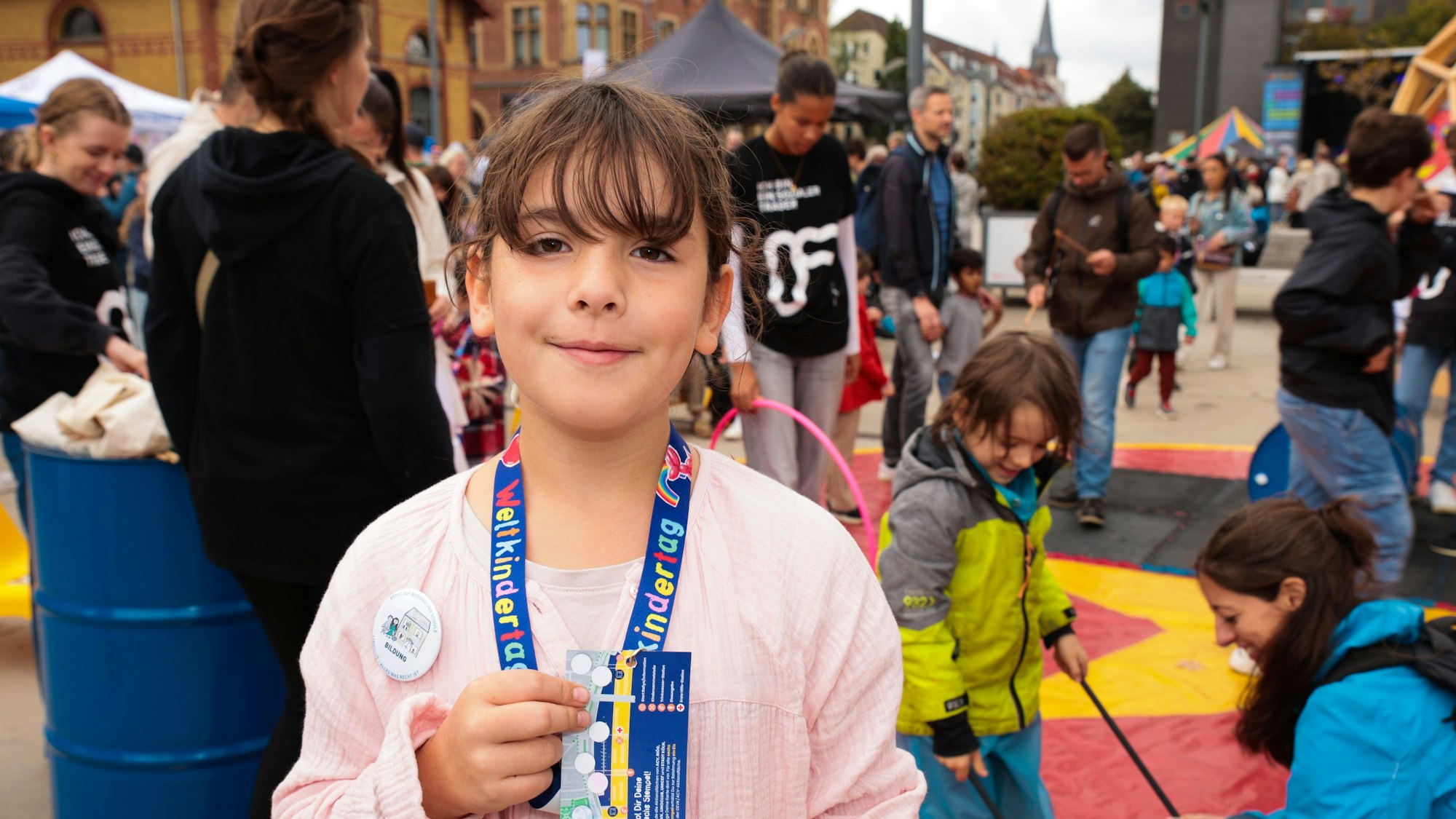 Ida, 8 Jahre, präsentiert beim Weltkindertag ihre Abzeichen, die sie bei der Rallye am Rheinauhafen bekommen hat.