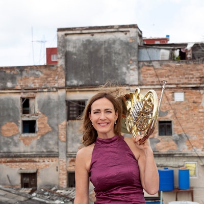 Sarah Willis steht vor einem kaputten Haus auf Kuba.