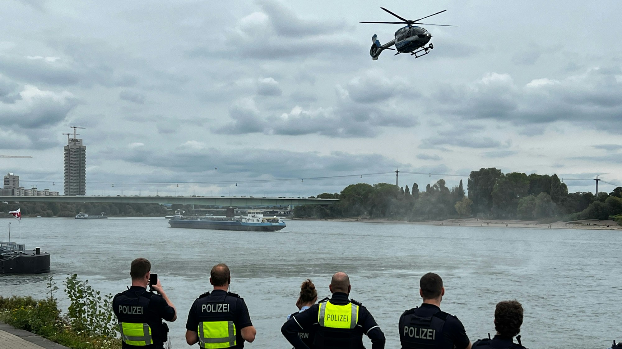 Polizei am Rhein, darüber ein Hubschrauber.