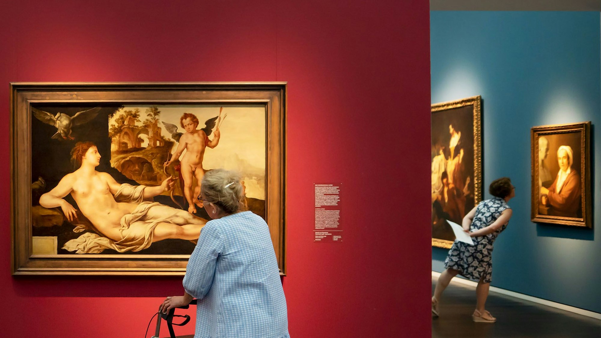 Das Bild zeigt zwei ältere Frauen, die sich eine Ausstellung im Museum ansehen.