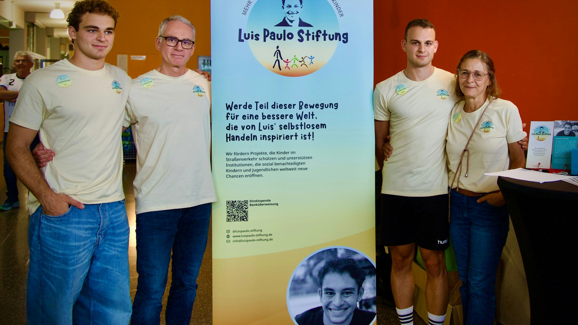 Zu sehen sind vier Menschen neben einem Aufsteller.