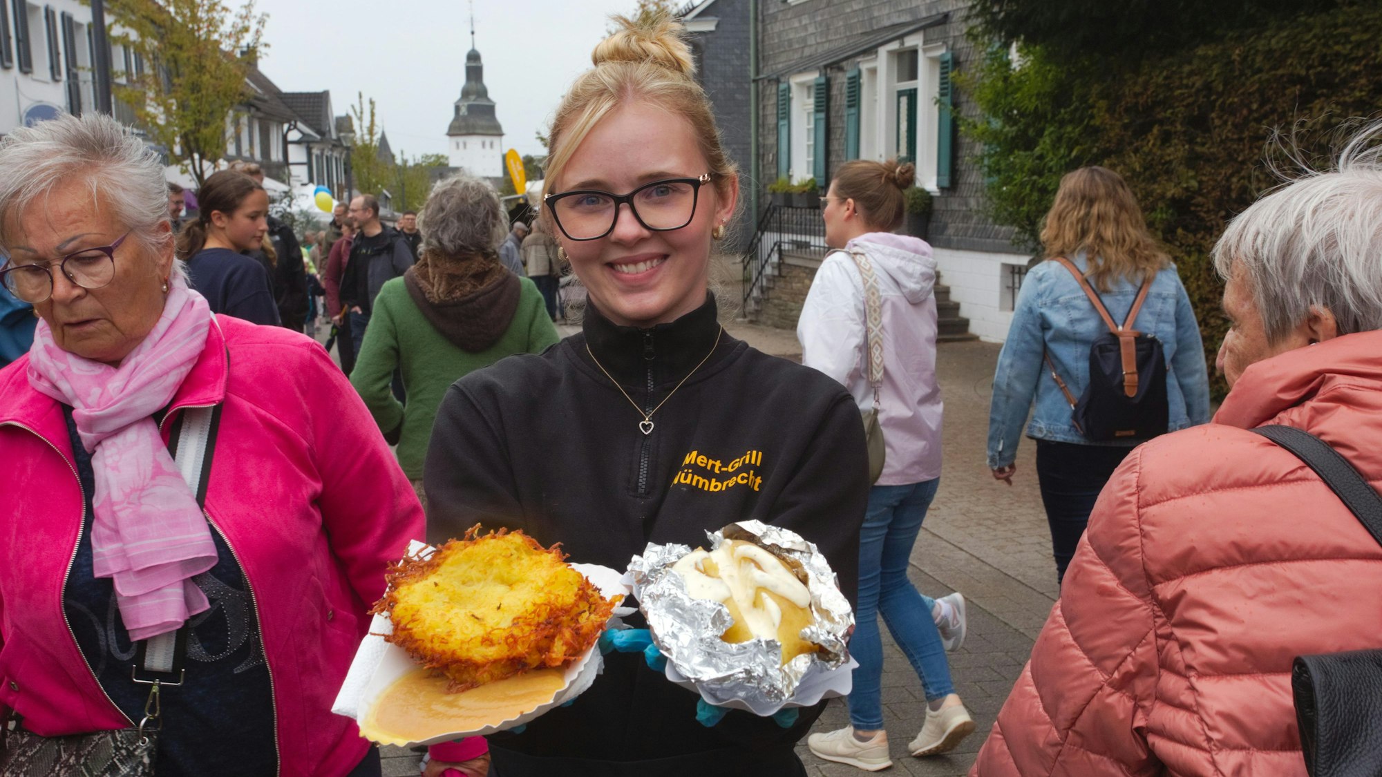 Eine Frau hält einen Reibekuchen und eine Ofenkartoffel in ihren Händen.