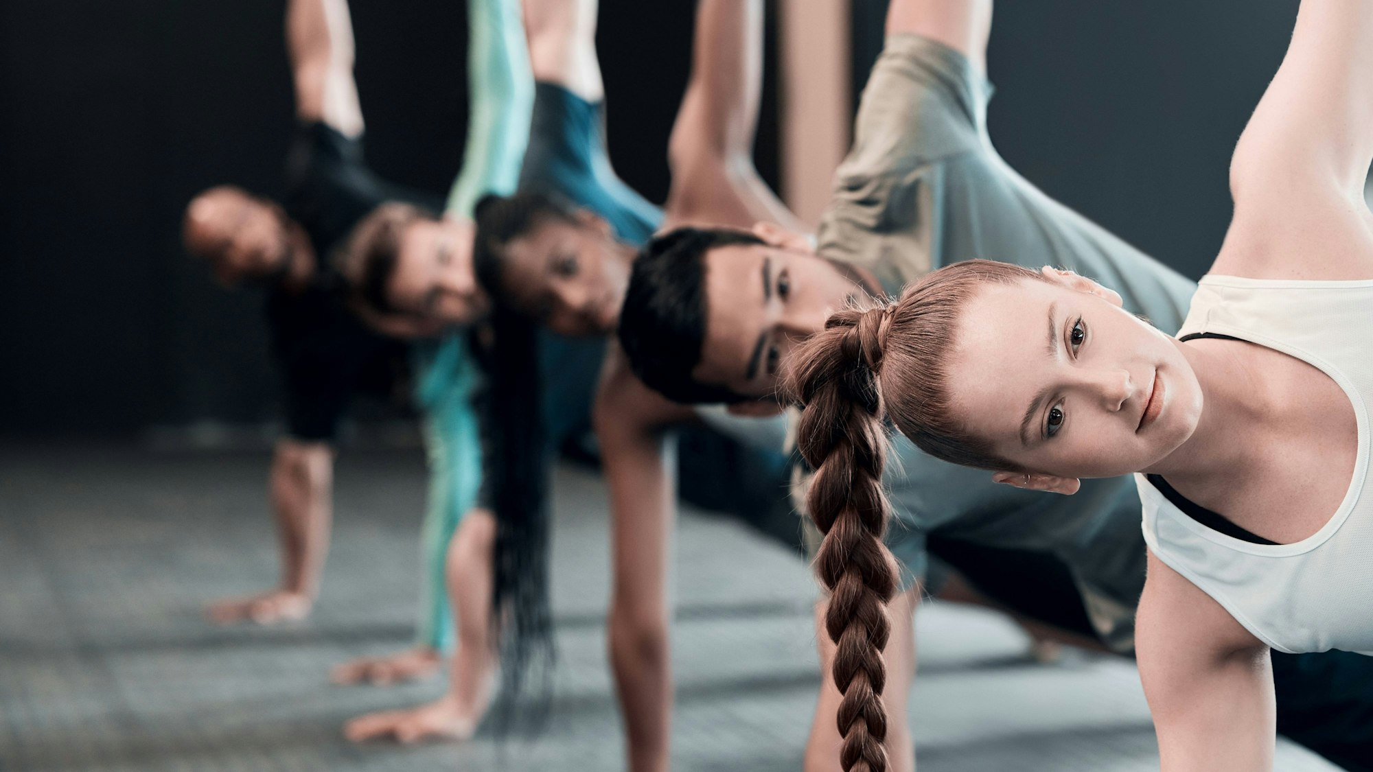 Eine Gruppe macht die Übung Side-Plank in einem Fitnessstudio.
