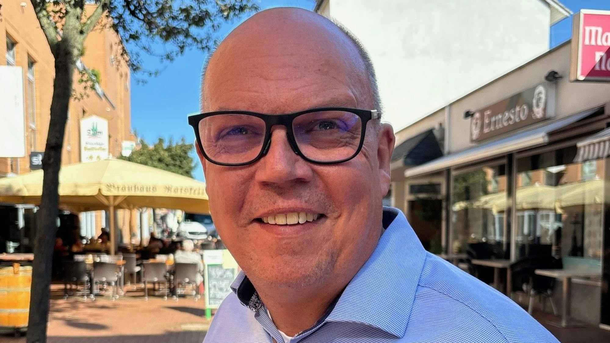 Auf dem Bild ist ein Portrait von Uwe Tietz zu sehen, er trägt ein hellblaues Hemd.