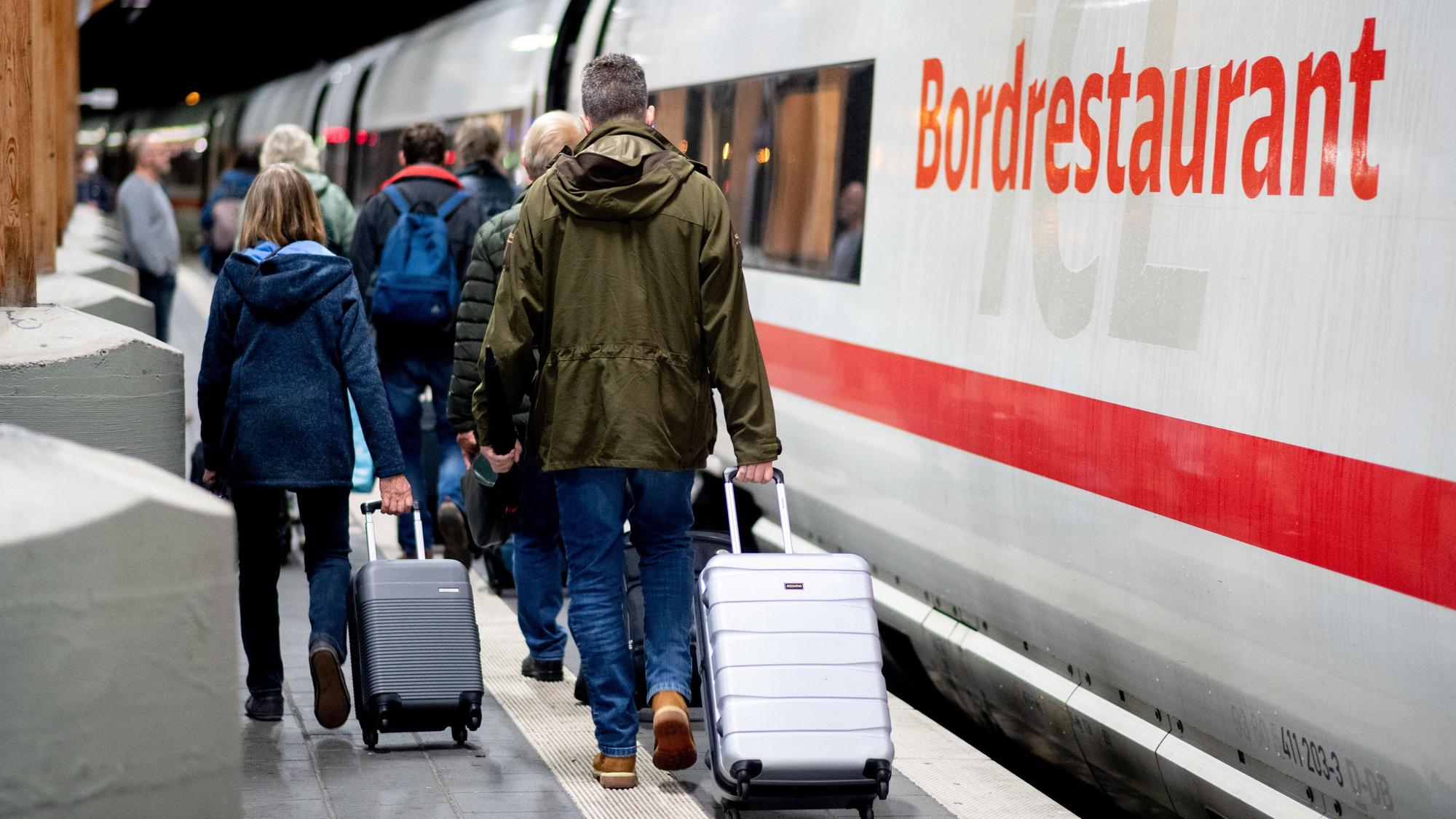 Fahrgäste gehen am frühen Morgen mit ihrem Gepäck über einen Bahnsteig am Hauptbahnhof, um in einen ICE der Deutschen Bahn (DB) einzusteigen.