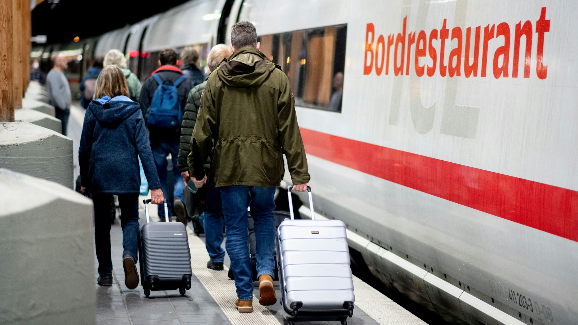 Fahrgäste gehen am frühen Morgen mit ihrem Gepäck über einen Bahnsteig am Hauptbahnhof, um in einen ICE der Deutschen Bahn (DB) einzusteigen.