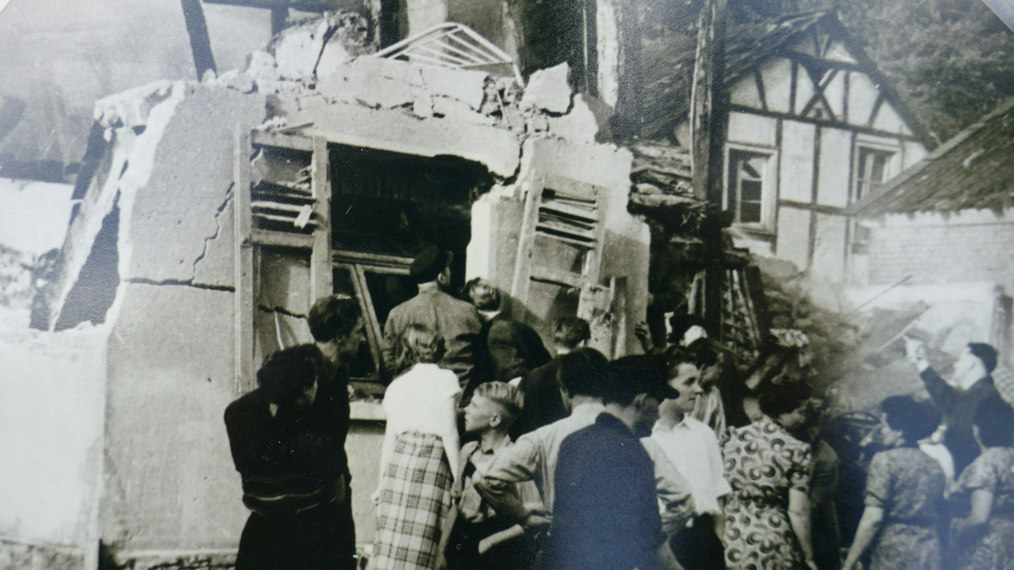 Menschen stehen vor einem zerstörten Haus.