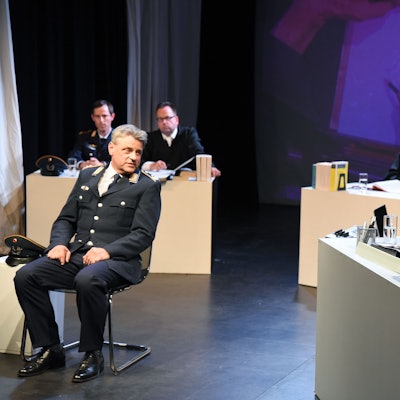 Auf der Bühne ist ein Gericht nachgestellt, wo ein Schauspieler als Luftwaffenoffizier seine Sicht schildert.