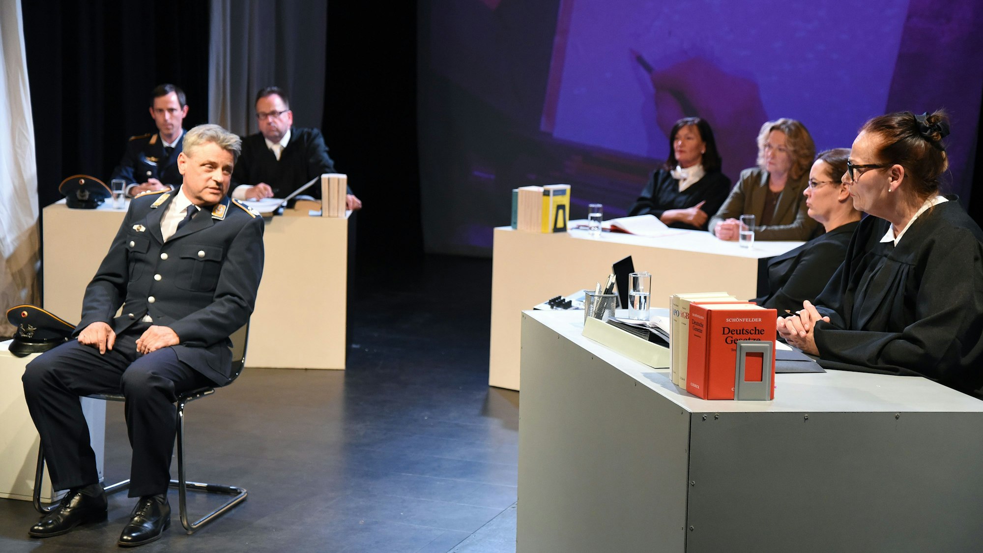 Auf der Bühne ist ein Gericht nachgestellt, wo ein Schauspieler als Luftwaffenoffizier seine Sicht schildert.