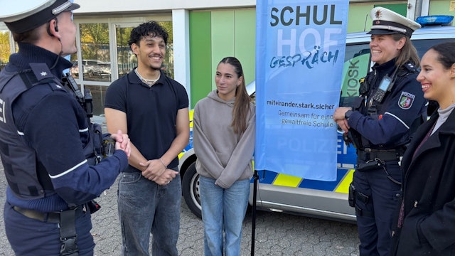 Die Polizeibeamten Jonas Tepe (l.) und Aldia Römer (2.v.r.) im Gespräch mit Gesamtschülern in Düsseldorf.